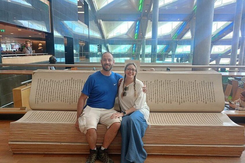 Two people sitting on a bench with a large book in the background. 4