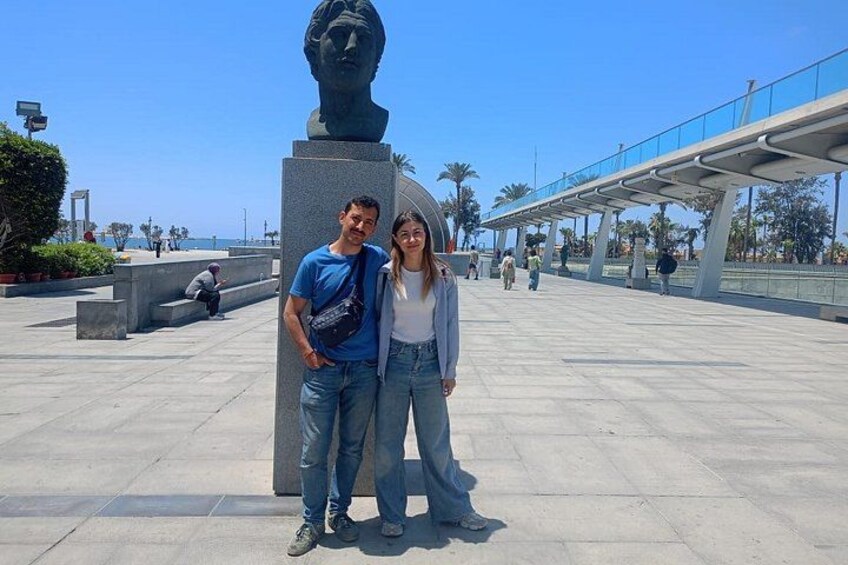 A man and woman posing in front of a sculpture in an open plaza with a clear sky. 5