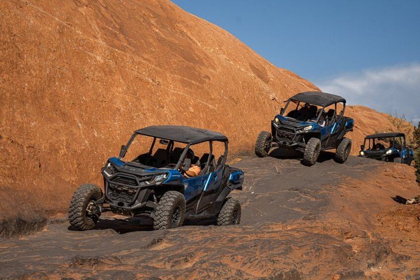 Two off-road vehicles on a rocky terrain with a large hill in the background. 2