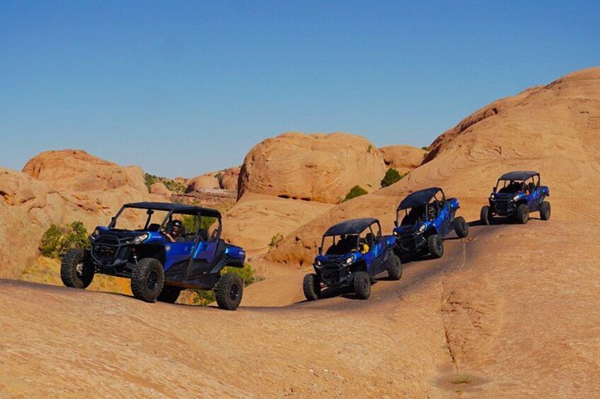 Four blue off-road vehicles on a desert trail. 2