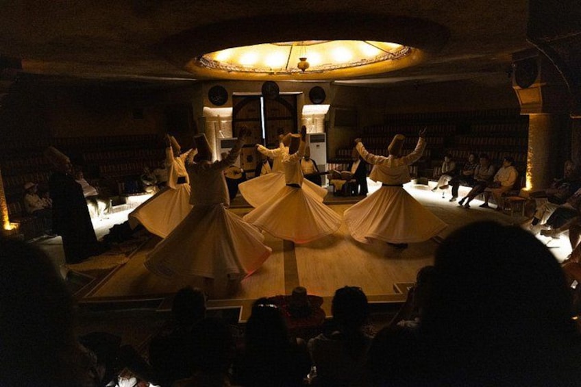 A dance performance in a dimly lit room with a circular stage and audience seated around. 3