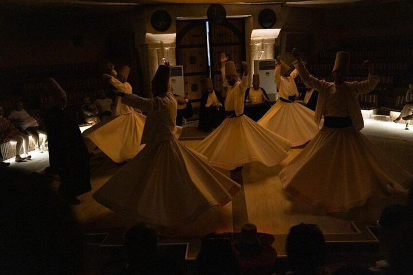 A group of dancers in traditional attire performing in a dimly lit room. 5