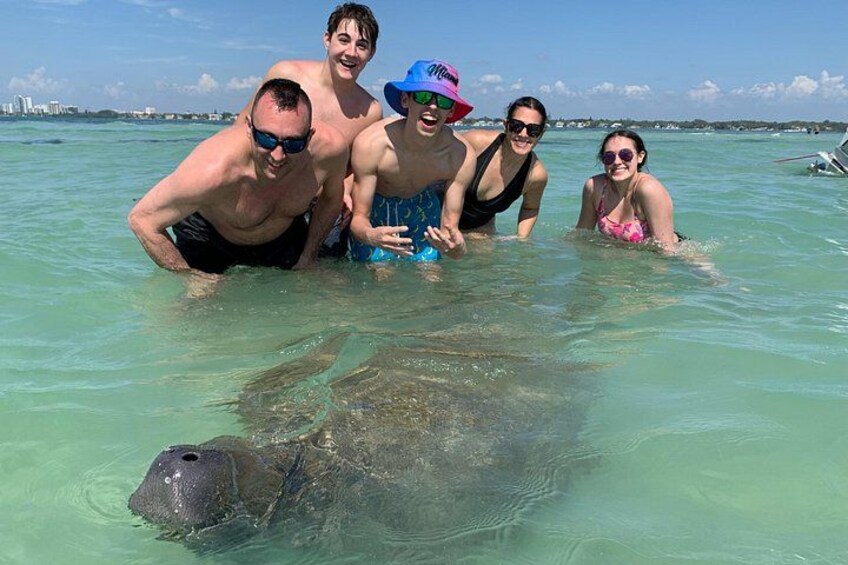 Een groep mensen in ondiep water met een zeeschildpad. 1
