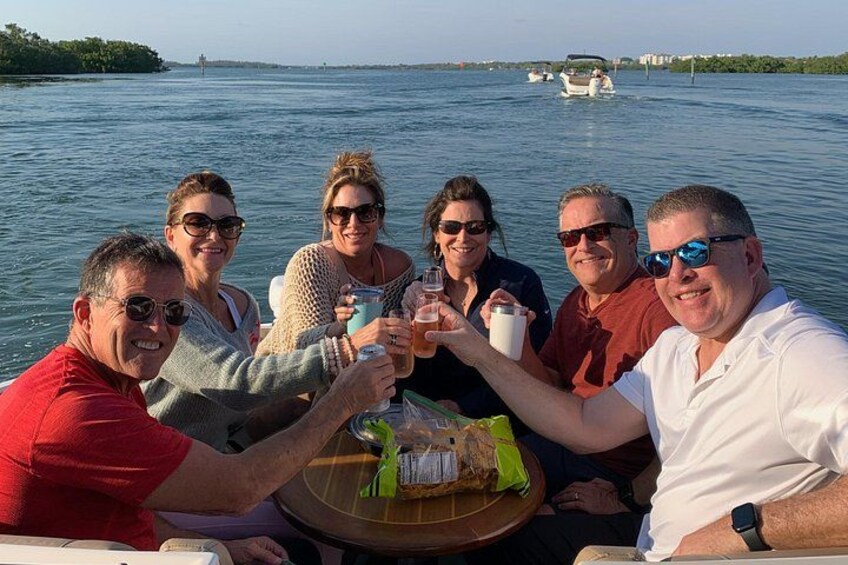 Een groep mensen proost met drankjes op een boot. 5