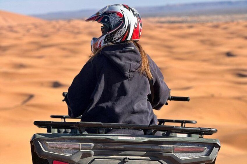 A person riding a quad bike in a desert landscape. 5