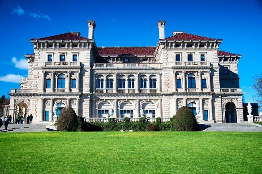 Un grand bâtiment historique à la façade symétrique, doté de nombreuses fenêtres et d’un toit recouvert de tuiles rouges. 3
