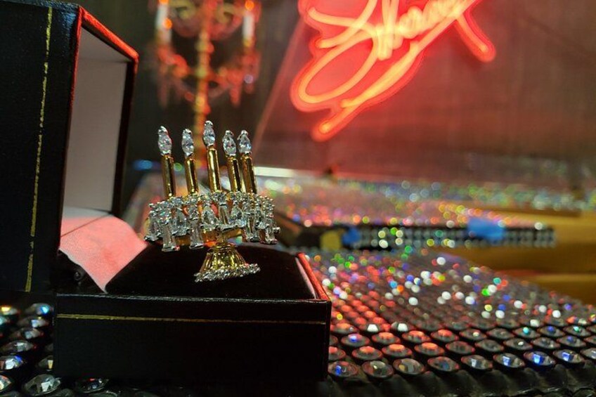 A menorah with candles in a box, with a blurred background of lights and a neon sign. 3