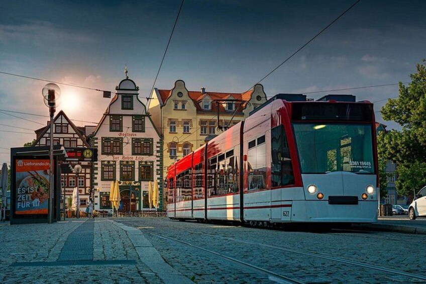 A tram on a cobblestone street, historic buildings, and a clear sky. 4