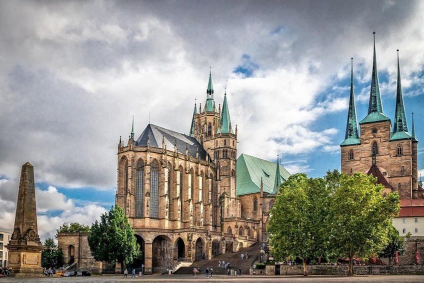 A historic cathedral with multiple spires and a large obelisk in the foreground. 3