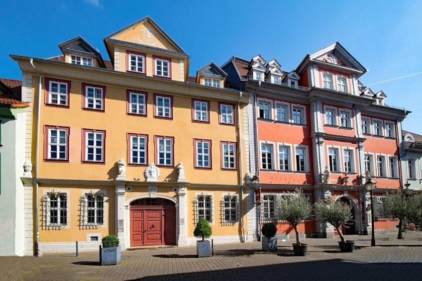 A multi-story building with a red door and multiple windows. 5