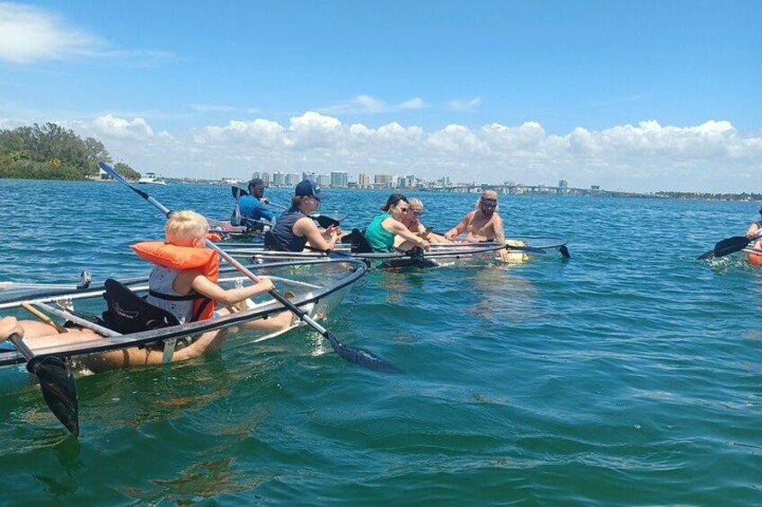 People rowing in a calm body of water with a city skyline in the background. 2