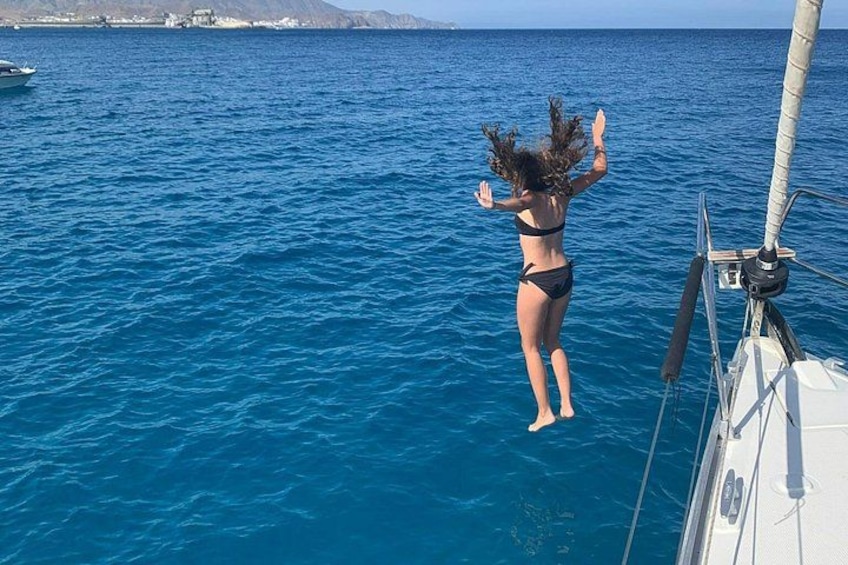 Een vrouw in een bikini springt vanaf een boot in de zee. 1