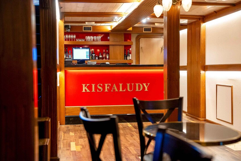 A bar area with a red counter labeled 'KISFALUDY,' wooden furniture, and a computer monitor. 3