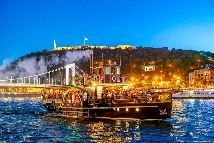 A steamboat with passengers, a bridge, and a hill with buildings in the background. 4