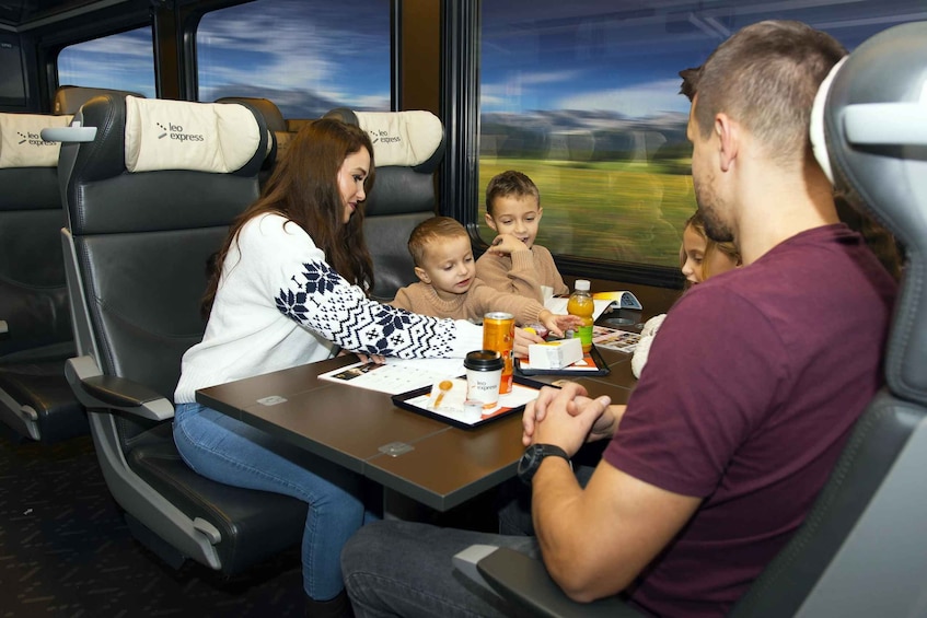 Une famille prend son repas à l’intérieur d’un wagon de train, sur des sièges portant l’inscription « Leo Express ». 4