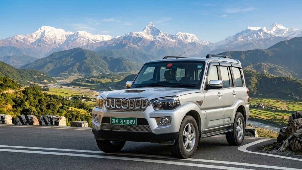 A silver SUV on a road with a mountainous landscape in the background. 1