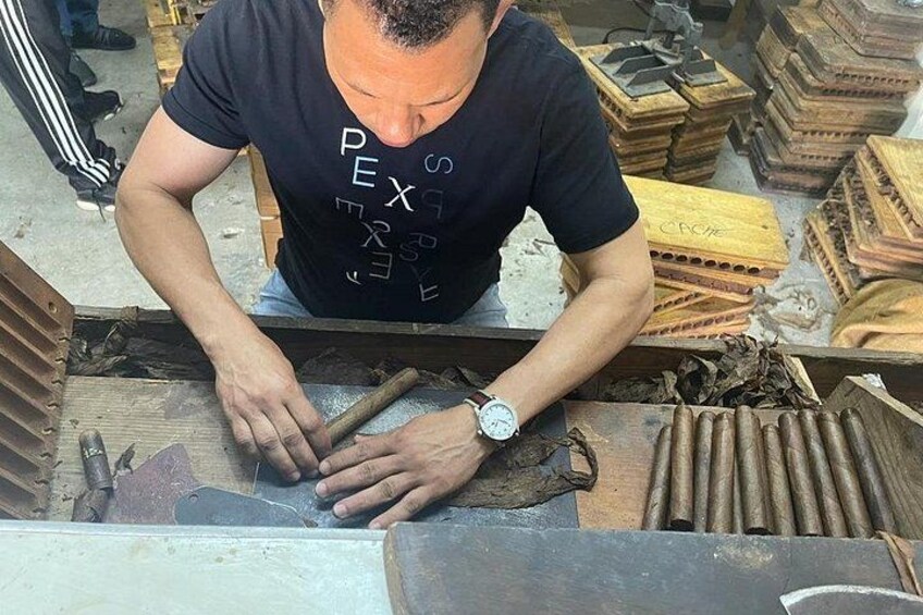 A person working with wooden cigar boxes and cigar bands. 5
