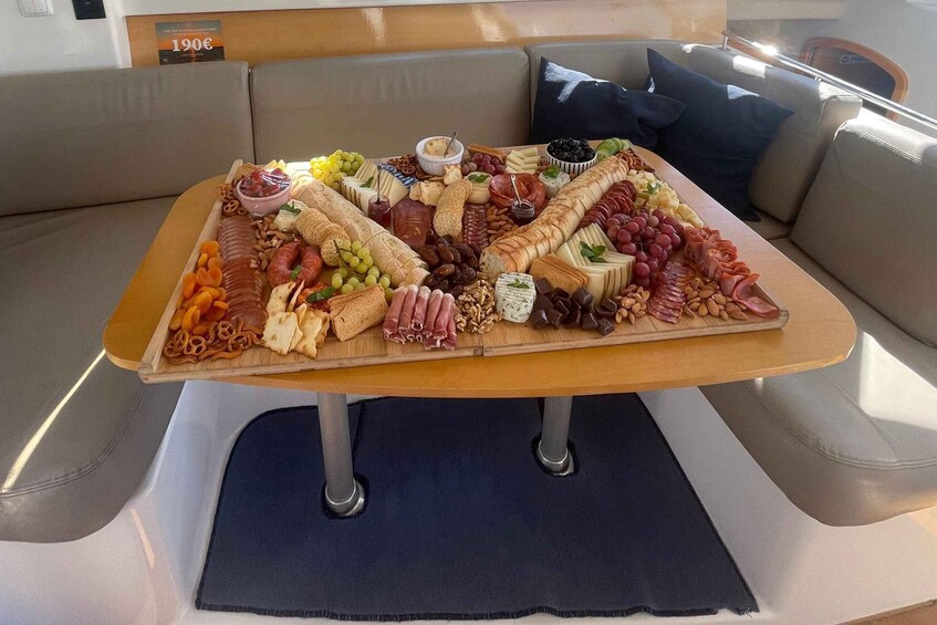 Une planche de charcuterie avec divers fromages, viandes, fruits et fruits secs, posée sur une table en bois à l’intérieur d’un véhicule. 5