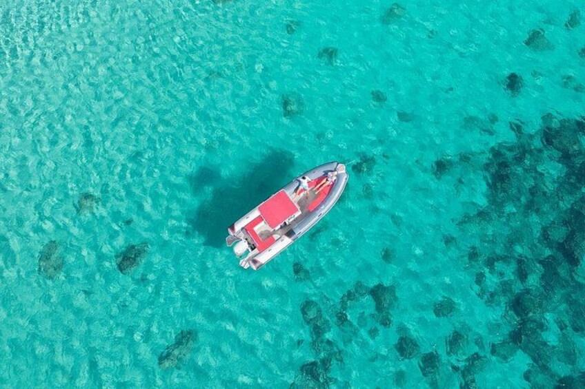 A boat on clear turquoise water with visible coral reefs. 5