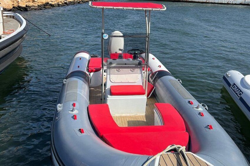 A motorboat docked at a marina with a red canopy and a wooden deck. 3