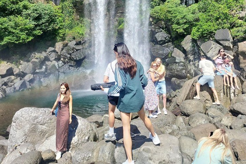 A group of people near a waterfall with rocks and greenery. 3
