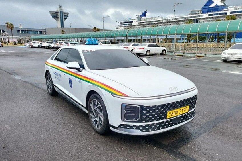 Un coche patrulla blanco con una franja roja, amarilla y verde estacionado en un estacionamiento. 3