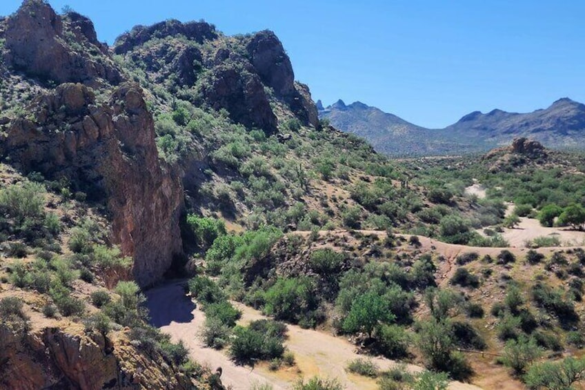 A desert landscape with rocky formations, sparse vegetation, and distant mountains. 5