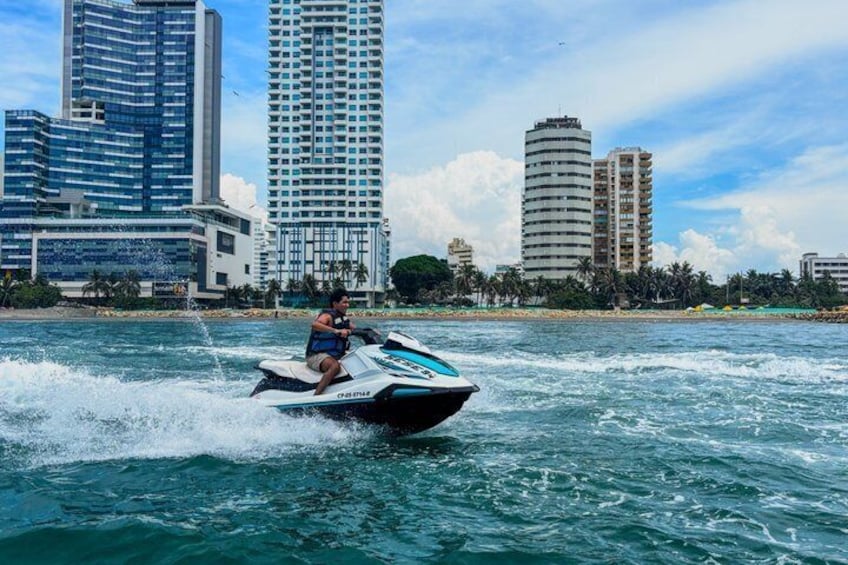 Une personne pratiquant le jet-ski sur une étendue d’eau, avec la silhouette d’une ville en arrière-plan. 1