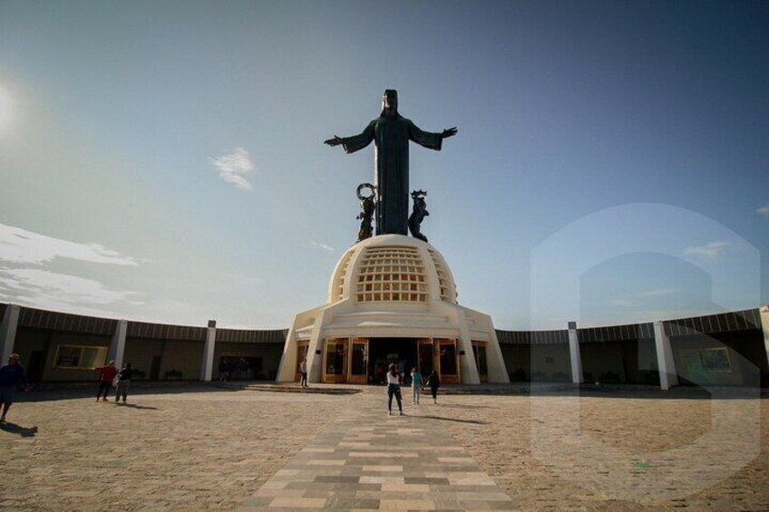 A large statue with outstretched arms in a plaza surrounded by buildings. 4