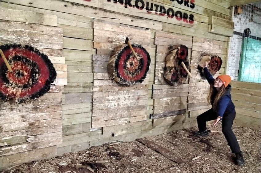 Un mur en bois orné de trois cibles circulaires, et une personne qui vise l’une d’entre elles avec un bâton. 5