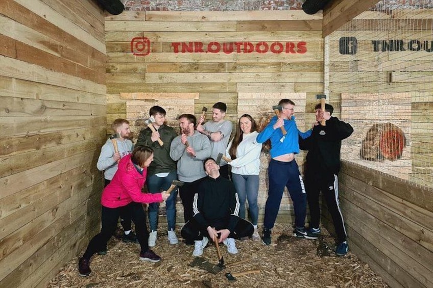Un groupe de personnes se trouve à l’intérieur d’un espace clos en bois, sur lequel est apposée une pancarte indiquant « TN Outdoors ». 2