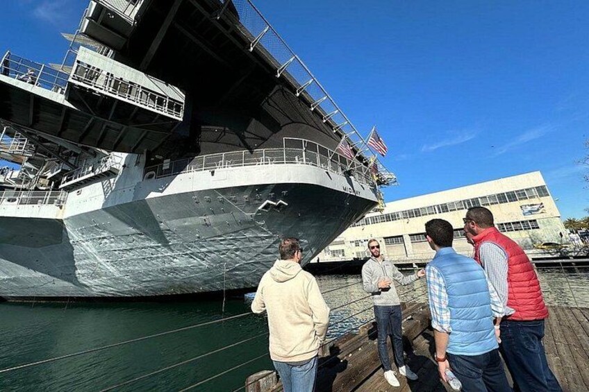 A large ship docked at a pier with people standing on the dock. 5