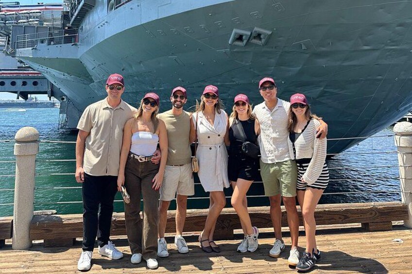 A group of people posing in front of a large ship docked at a pier. 4