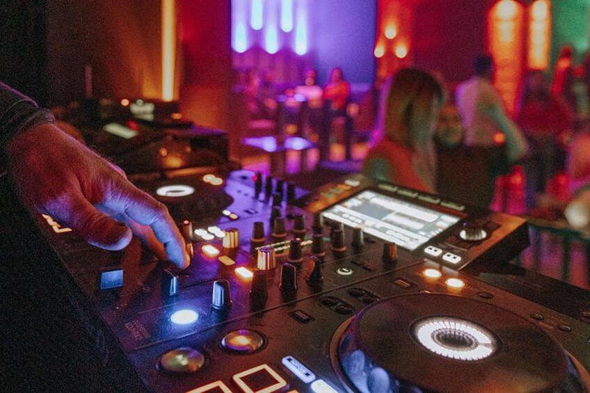A DJ mixing music with a turntable and control panel. 1
