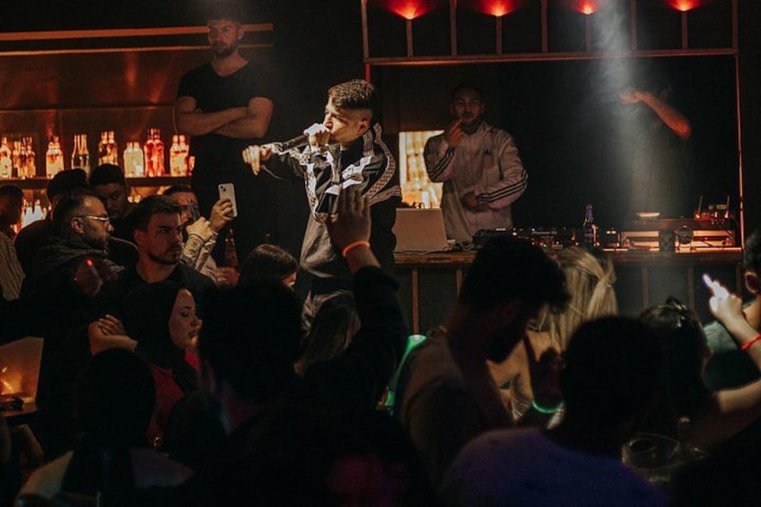 A bar with people dancing and a DJ performing. 5