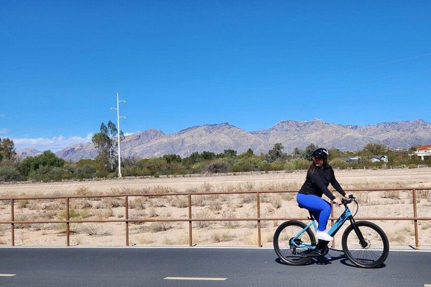 A person riding a bicycle on a road with a mountainous landscape in the background. 2