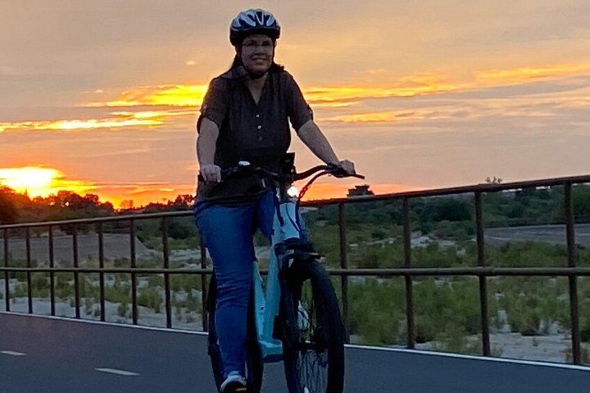 A person riding a bicycle on a bridge during sunset. 5