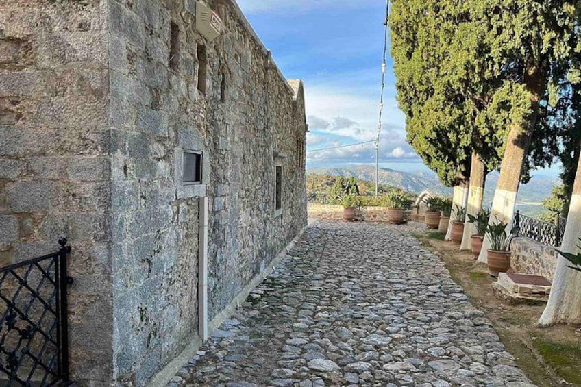 A stone pathway, a stone building, and a tree-lined view. 3