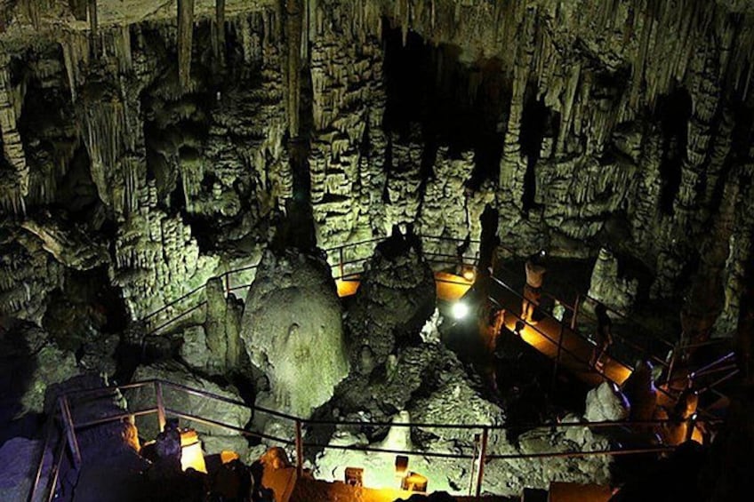 A cave with stalactites and stalagmites, a large rock formation, and a walkway. 1