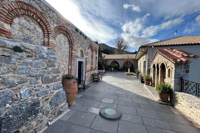 A courtyard with stone buildings, a paved walkway, and potted plants. 5