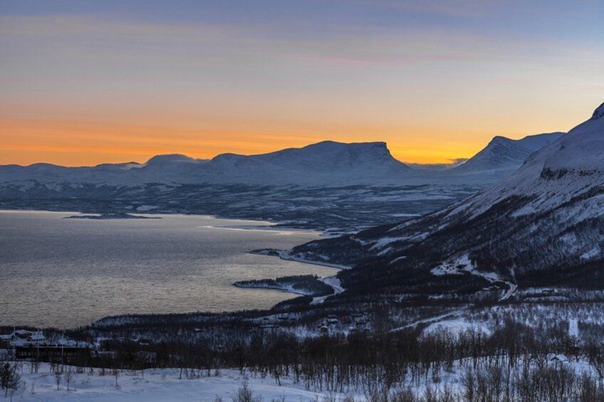 A snow-covered landscape with a lake and mountains during sunset. 3