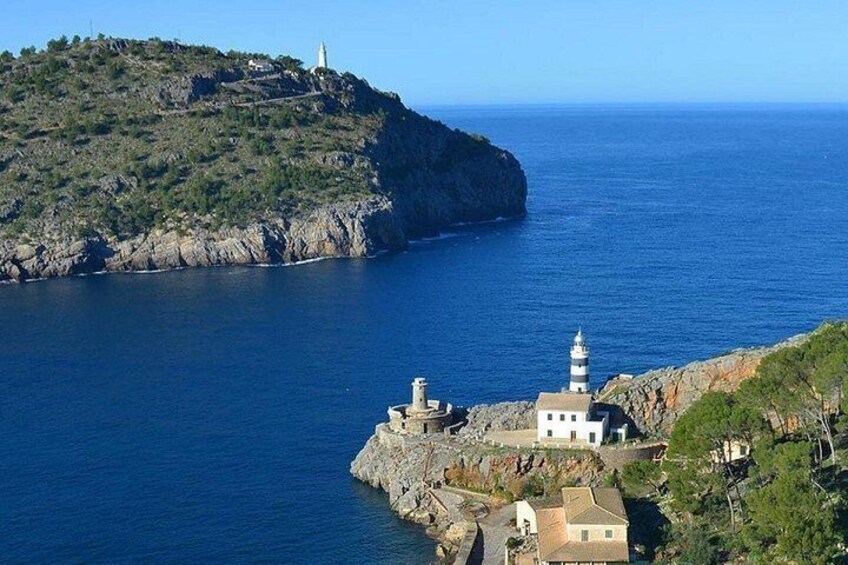 Paisaje costero con un faro, terreno rocoso y un pequeño edificio en un acantilado. 3