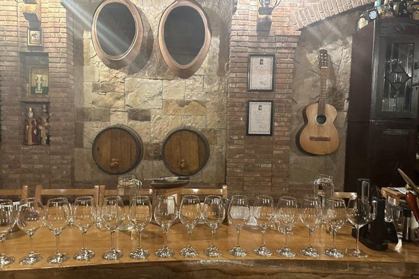 Un bar con barriles de madera, una guitarra y copas de vino sobre la barra. 2