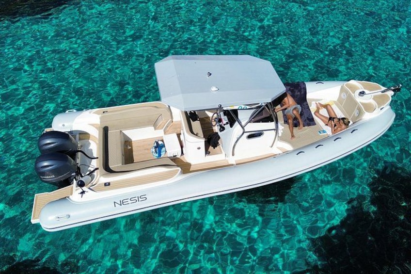 Een boot met de naam 'NESIS' op helder turquoise water. 1
