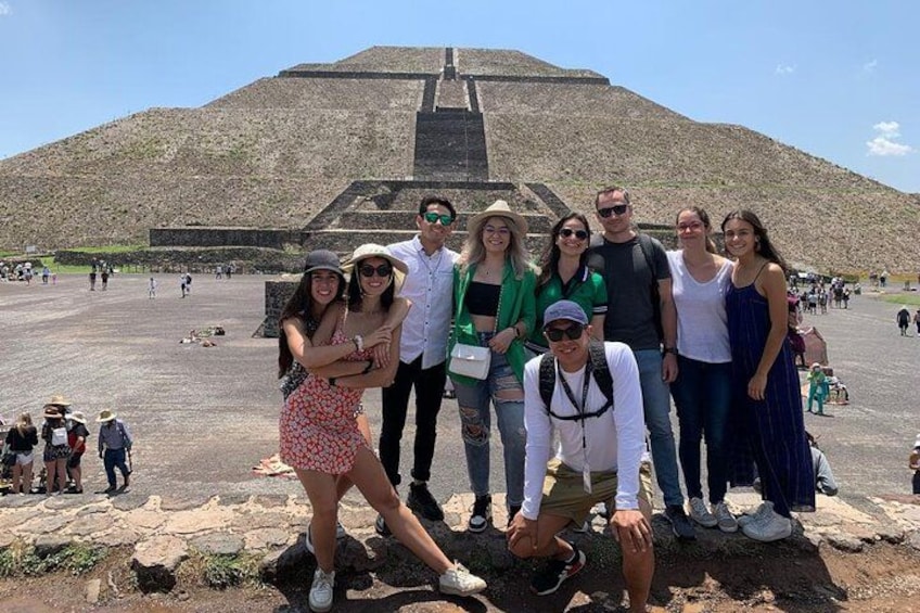 A group of people posing in front of a large pyramid structure. 1