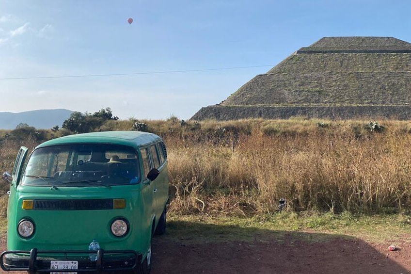Una furgoneta verde estacionada en un camino de tierra con una gran pirámide al fondo. 2