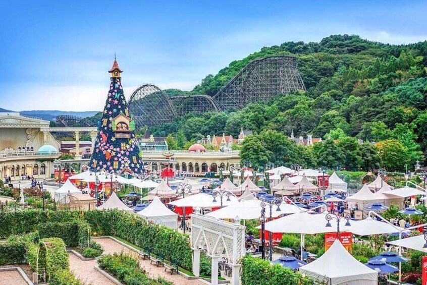 A festive outdoor market with tents and a large decorated Christmas tree. 1