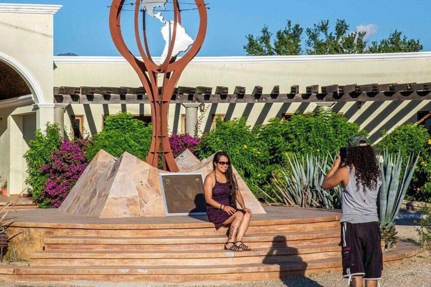 Una mujer sentada en unos escalones con una escultura y plantas al fondo. 3