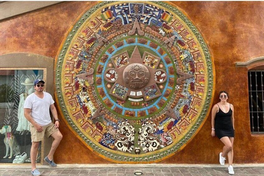 A large circular mural with intricate designs and a central emblem on a building wall. 3