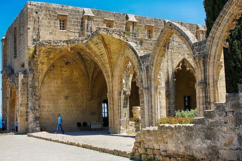 Un bâtiment historique en pierre, doté d’arcades et d’une porte cintrée, avec une personne qui marche devant. 3